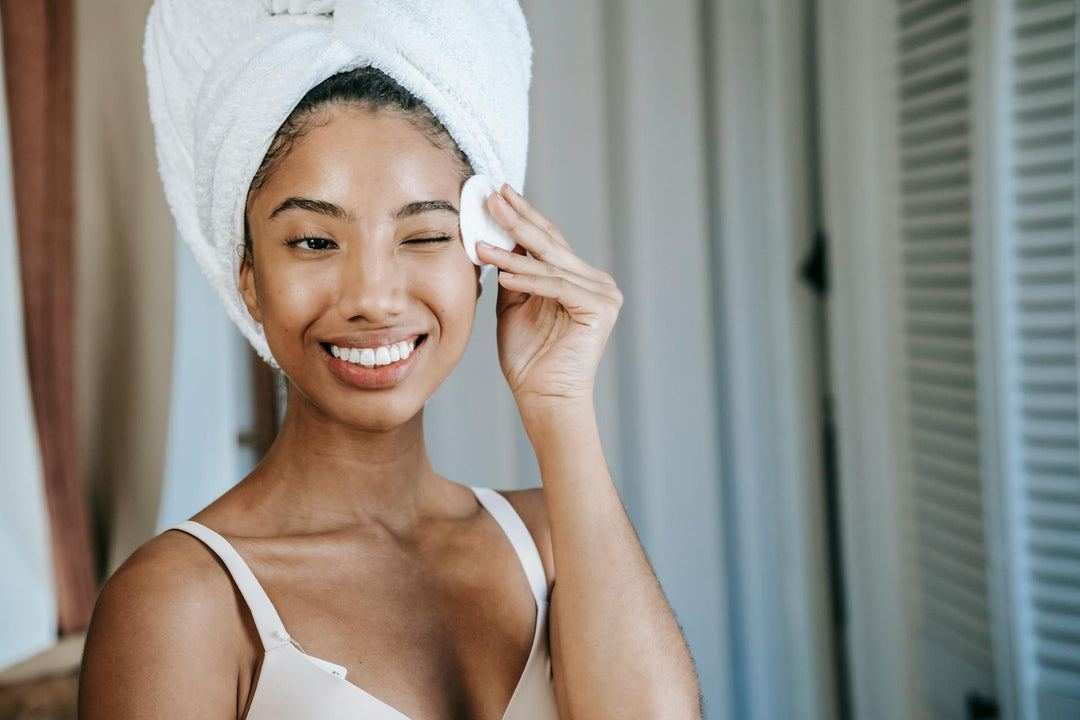 Black woman in a towel headwrap doing a Korean skincare routine