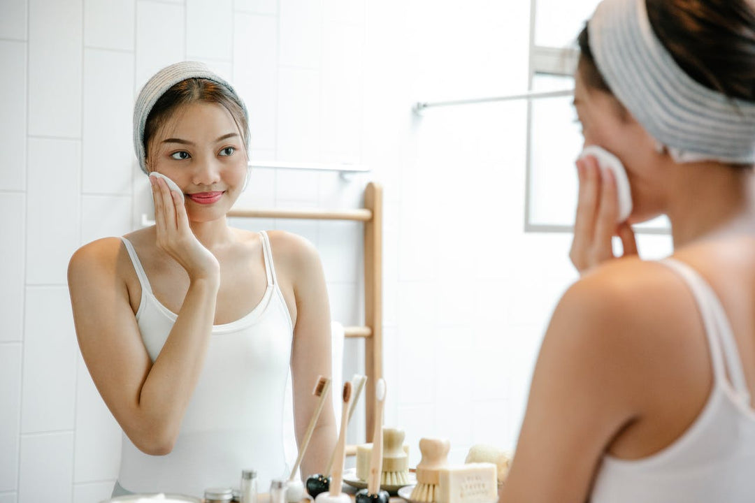 Girl in front of a mirror wiping a Korean skincare toner pad on her face